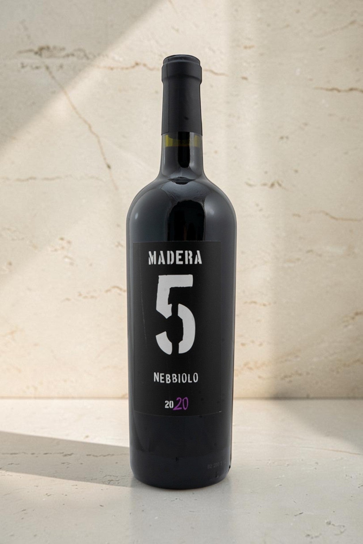 Botella de vino tinto Wellnex Nebbiolo Madera 5 cosecha 2020 con etiqueta negra minimalista sobre fondo de piedra