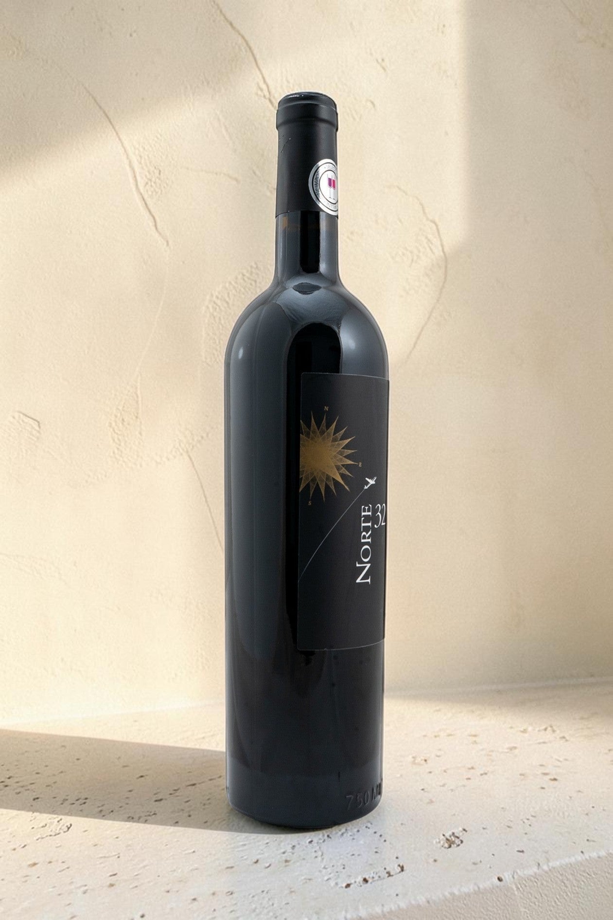 Botella de vino tinto Wellnex Norte 32 Etiqueta Negra con etiqueta elegante sobre fondo texturizado claro