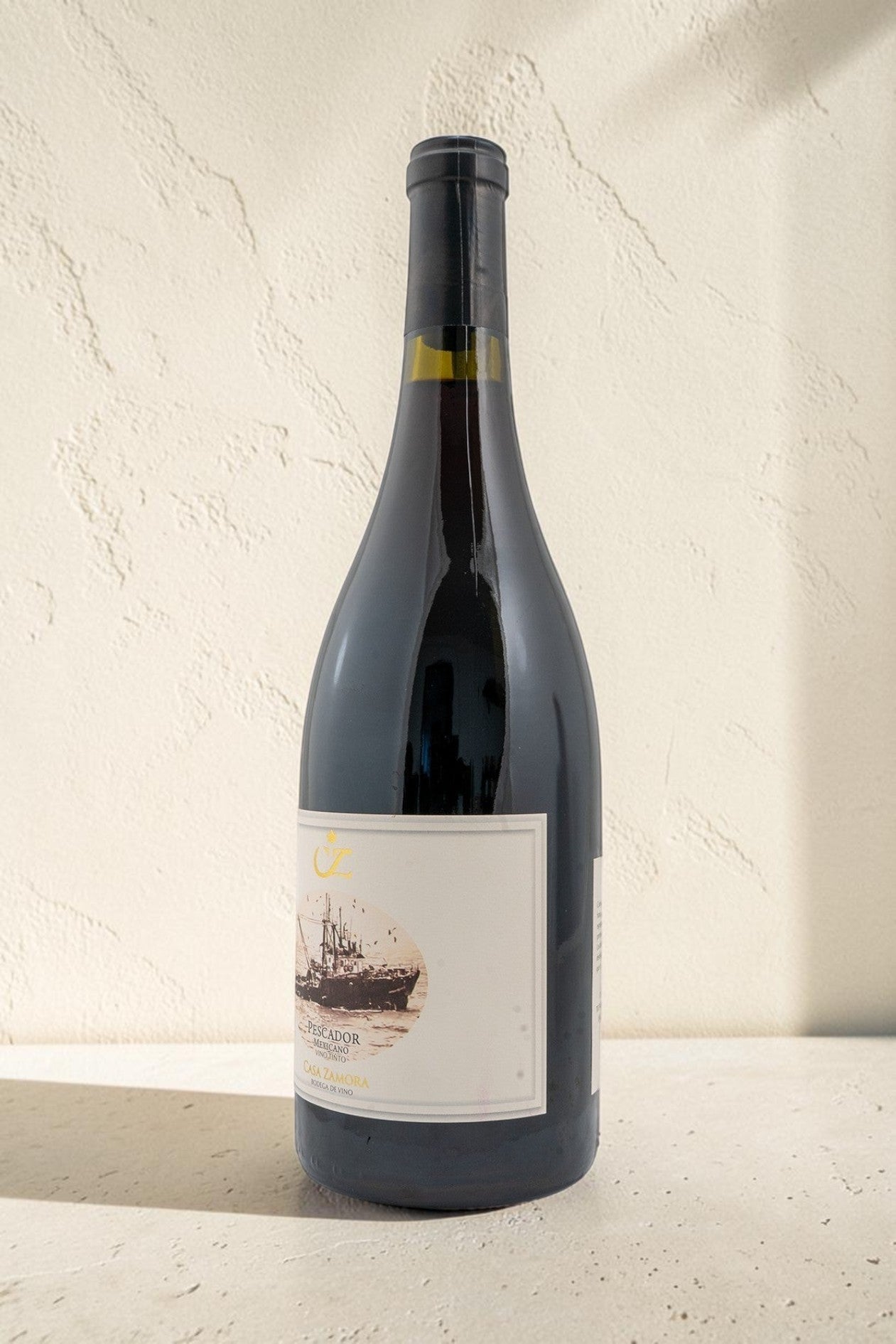 Botella de vino tinto Pescador de Wellnex con etiqueta ilustrada sobre fondo texturizado color crema