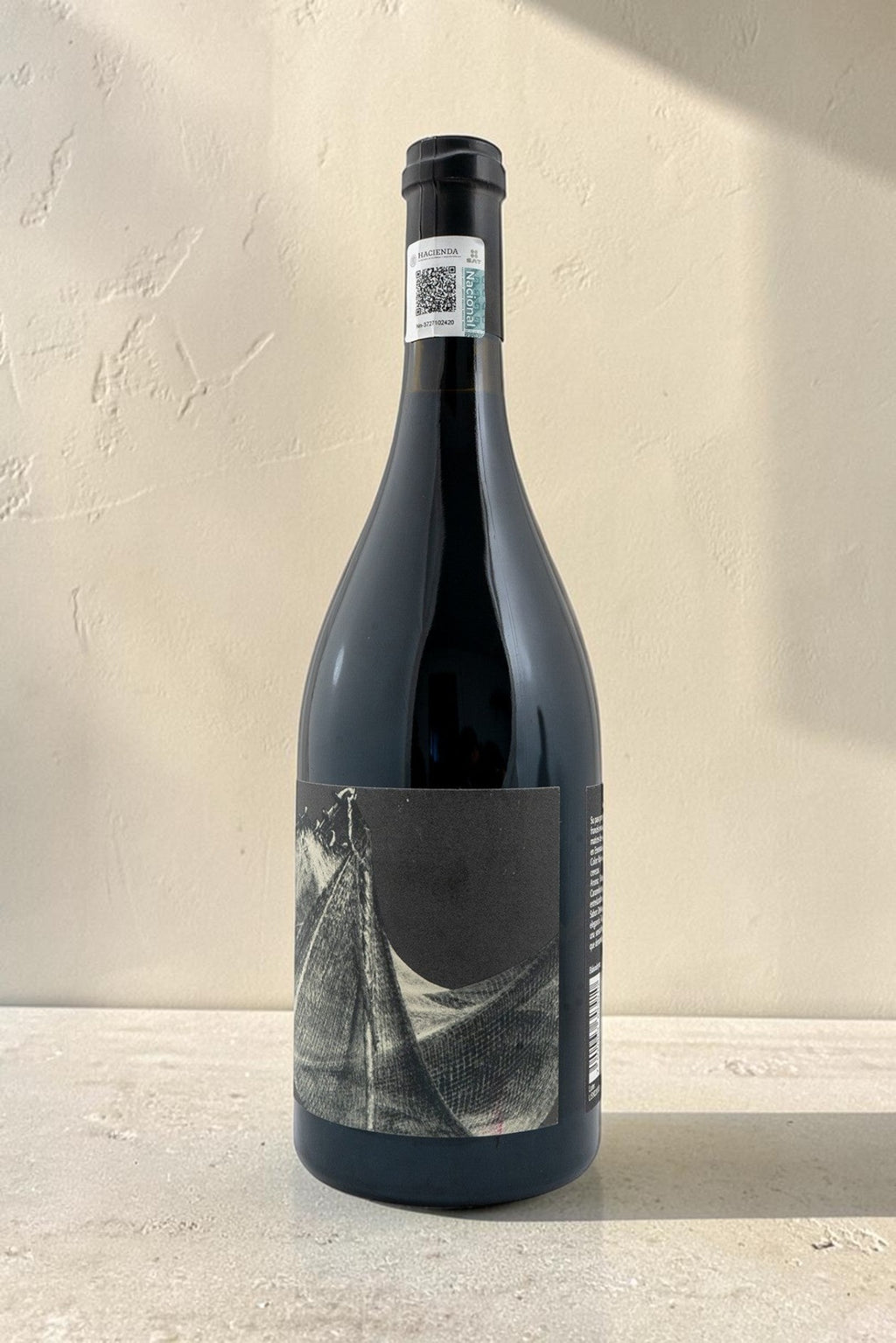 Botella de vino tinto Redes de Wellnex con etiqueta artística en tonos oscuros sobre fondo neutro iluminado