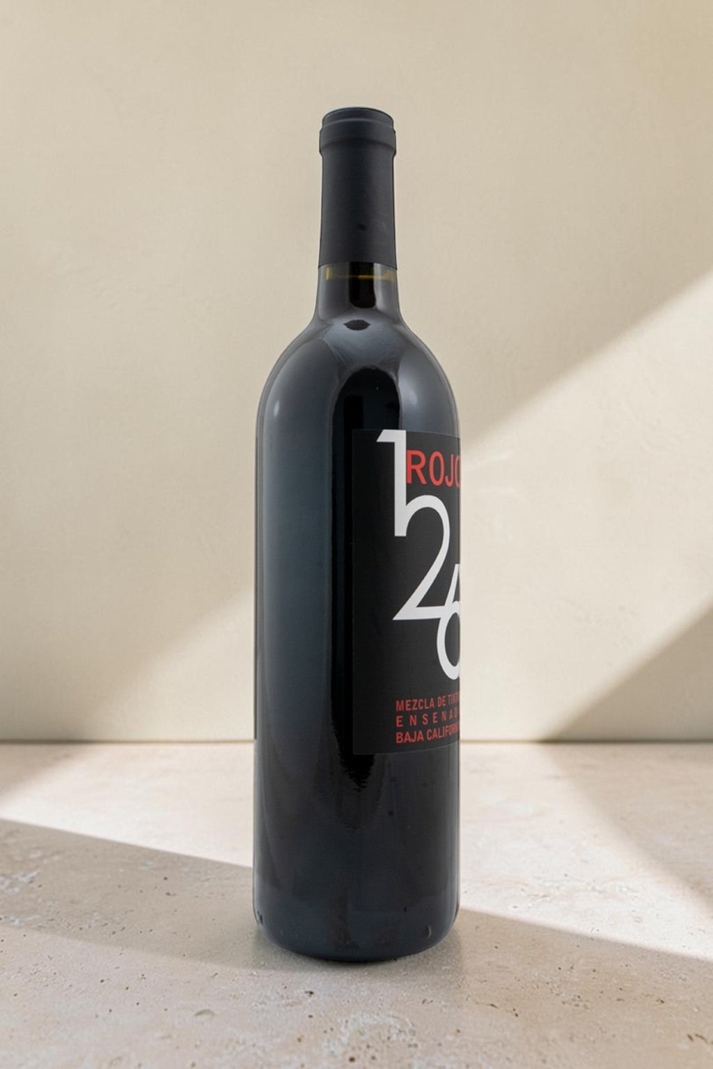 Botella de vino tinto Wellnex Rojo 126 con etiqueta negra moderna sobre fondo neutro iluminado