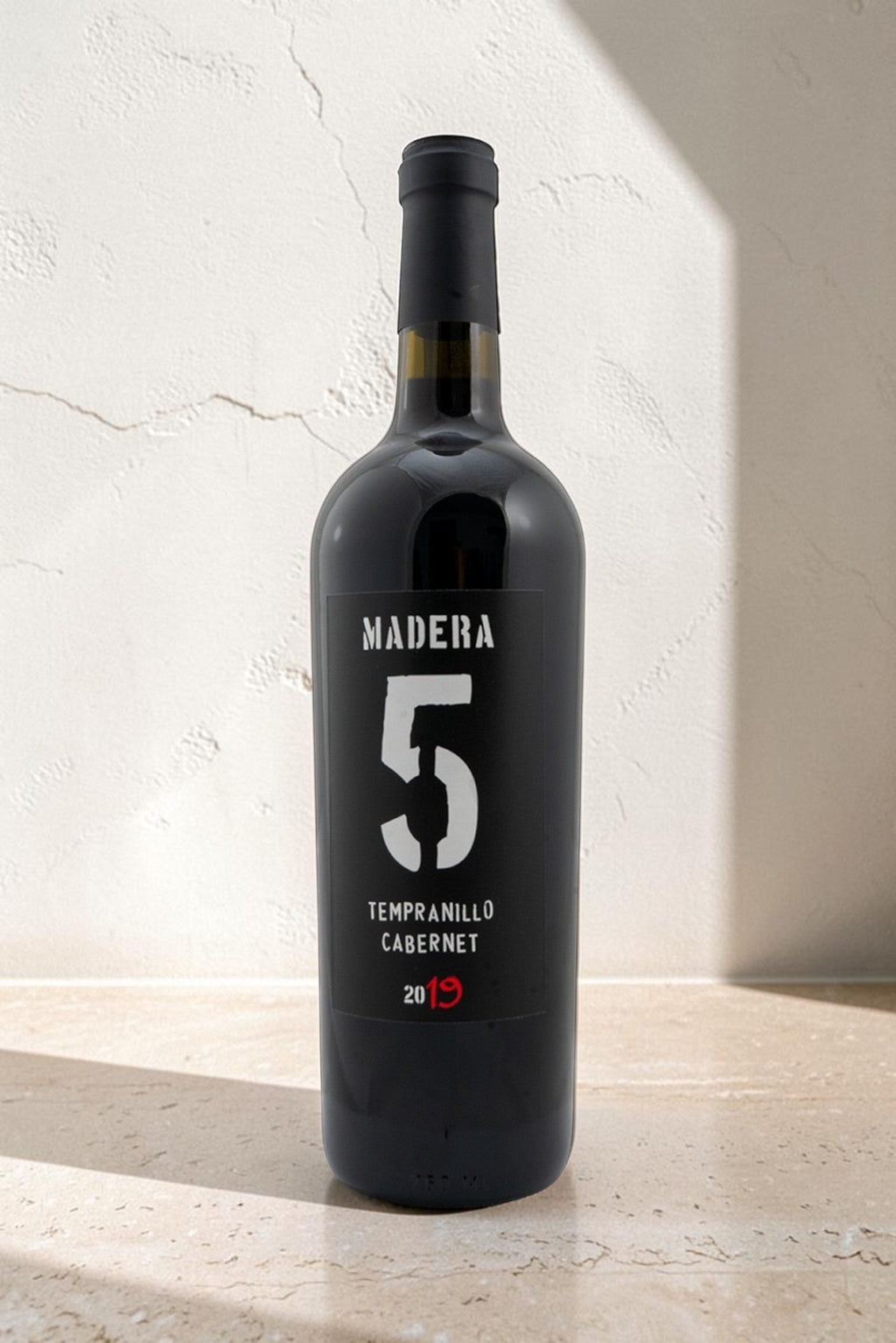 Botella de vino tinto Wellnex Madera 5 Tempranillo Cabernet 2019 con etiqueta negra sobre fondo neutro