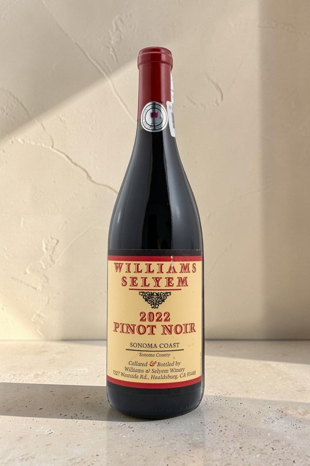 Botella de vino tinto Wellnex Williams Selyem 2022 Pinot Noir de Sonoma Coast sobre superficie clara