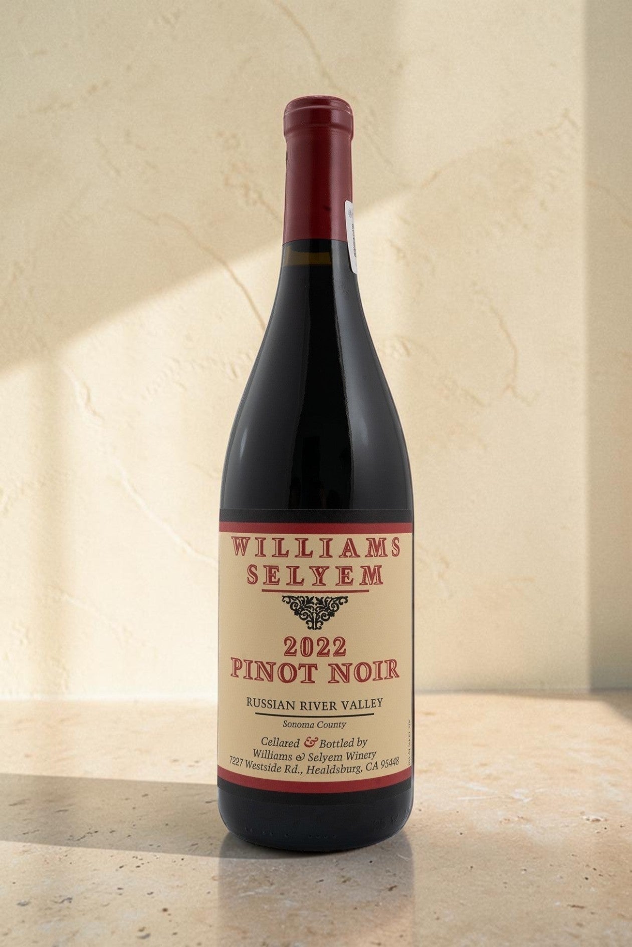 Botella de vino tinto Wellnex Williams Selyem Pinot Noir 2022 de Russian River Valley sobre superficie de piedra
