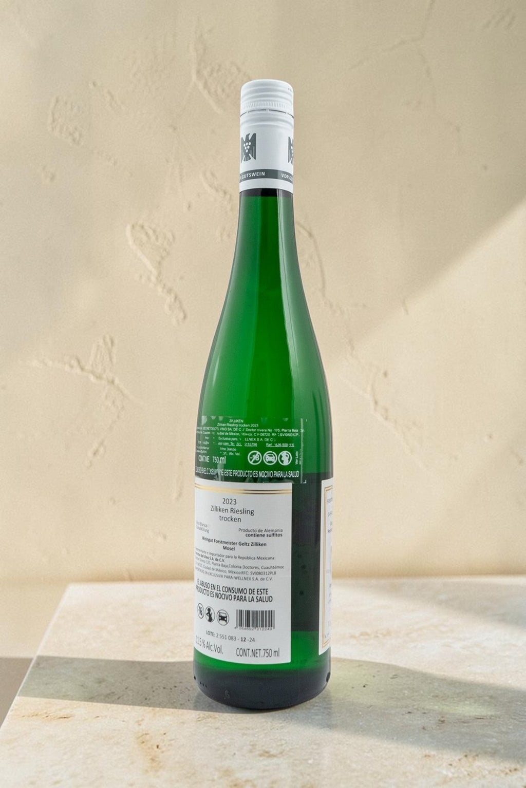 Botella de vino blanco Wellnex Weingut Zilliken Riesling Trocken 2023 con etiqueta informativa sobre fondo neutro.