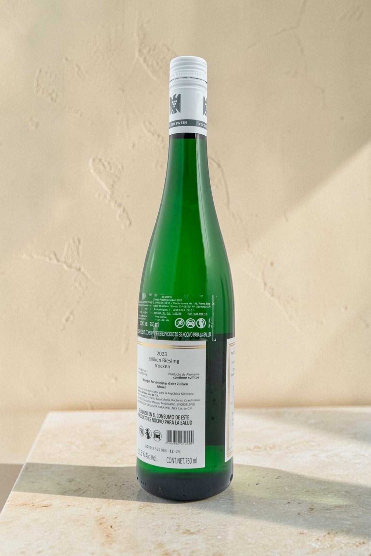 Botella de vino blanco Wellnex Weingut Zilliken Riesling Trocken 2023 con etiqueta informativa sobre fondo neutro.